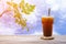 Ice coffee or cola on wood table with tree and clouds sky background