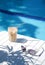 Ice coffee Cyprus Frappe Fredo against blue clear water of the swimming pool, on white table, with sunglasses . Summer