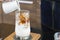 Ice coffee latte on a wooden table with black coffee being poured into it showing the texture and refreshing look of the drink