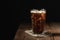 Ice coffee in a tall glass over and coffee beans on a old rustic wooden table. Cold summer drink on a dark background