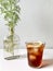 Ice coffee topped with lemon served in round glass. With coriander plant on the side.