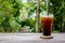 Ice coffee on wood table with green nature background. Copy space