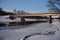 Ice cold river stream running underneath old weathered metal car bridge