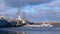 Ice covered pier with ship after storm. Blue sky with white clouds sanctified sun