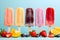 Ice cream bars in a variety of colors, bright, lively, and delicious, along with a variety of fruits. On a pastel blue background