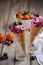 Ice cream with blueberries and strawberries in waffle cone on rustic wooden background