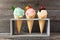 Ice cream cone assortment against a wood background, mint, strawberry and vanilla flavors