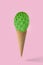 Ice cream cone with green cactus on pink background.