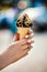 Ice cream cone with nuts and chocolate in hands