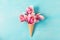 Ice cream cone with pink magnolia flowers bouquet on blue background. Minimal spring concept. Flat lay. top view