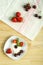 Ice cream dessert with strawberries and cherries in a gourd on a wooden table next to scattered berries.