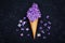 Ice cream of lilac flowers in waffle cone on black background from above, beautiful floral arrangement, vintage color, flat lay