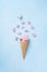 Ice cream of pink flying flowers in waffle cone on pastel blue background top view. Beautiful floral composition, flat lay styling