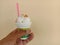 Ice cream in plastic cup with bean in hand  on cement wall background closeup.