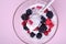 Ice cream with raspberry, blackberry berries with spoon in glass bowl on pink background