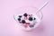 Ice cream with raspberry, blackberry berries with spoon in glass bowl on pink background