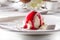 Ice cream scoop with berry syrup on white plate close-up