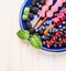 Ice cream sorbet pops with different summer berries and mint in blue plate on white wooden background