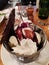 Ice cream sundae with whipped cream, chocolate and cherry in a metal bowl
