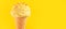 Ice cream. Vanilla, banana or lemon flavor icecream in waffle cone over yellow background. Sweet dessert