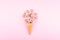 Ice cream waffle cone with colorful flowers and pink chocolate on pink background. Flat lay. Minimal gift birthday concept