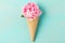 Ice cream waffle cone with pink peony flower on blue background. Minimal spring concept. Flat lay
