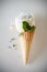 Ice creams immitation in waffle cone decorated mint leaves and flowers. Peonies flower in waffle cone with mint leaves.