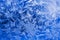 Ice crystals close up on a window pane in winter. Dark blue and white background or wallpaper. Mystical fabulous abstract lase.