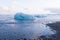 Ice cube breaking front glacier on black small rock beach