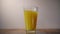 An ice cube is falling into a close-up of a glass of orange juice, creating a splash.