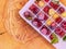 Ice cubes with raspberries. Ice tray with berries on wood background.