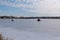 Ice fishing; frozen lake surface in winter with ice fisherman and an ice shanty on the lake.