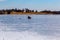 Ice fishing; frozen lake surface in winter with ice fisherman on the lake.