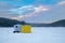 Ice fishing tent on a frozen lake at sunset. Fisherman camp on a peaceful winter evening