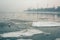 Ice floes float in the calm Azov Sea against the background of the port of Taganrog in early winter