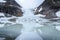 Ice front of norwegian glacier Steindalsbreen surrounded by high mountains mirroring in the glacial lake with little icebergs