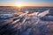 Ice on a frozen lake in sunlight at sunset. Winter nature landscape. Scenery icy crystalline structure illuminated by the evening