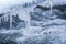 Ice on frozen river, closeup detail, water flows over rocks forming waves and bubbles - winter background
