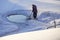 Ice hole in the lake in winter is equipped with a ladder for launching. Man cleans ice hole