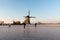 Ice skaters on a frozen windmill canal at sunrise moment