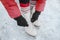 Ice skating woman tying laces of figure skates shoes to go skate at rink. Winter sport people. Closeup of hands and feet