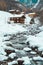 Ice and snow covered creek on a cold winter day infront of traditional wooden cabins of little mountain village