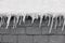 Ice stalactites with snow on a roof detail. Winter time