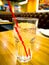 Ice water with red suction tube. The glass is placed on the wood