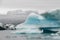 An iceberg afloat in front of an icelandic glacier