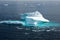 Iceberg in sunlight shining in white and turquoise in dark blue Arctic Ocean, Greenland