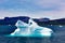 Iceberg in sunlight shining in white and turquoise over dark blue Arctic Ocean, Greenland