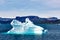 Iceberg in sunlight shining in white and turquoise over dark blue Arctic Ocean, Greenland