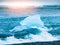 Icebergs sphashed by sea waves on black beach at sunrise time near Jokulsarlon glacier lake, Iceland