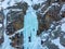 Iceclimber climbing steep frozen icefall. Extreme winter sports